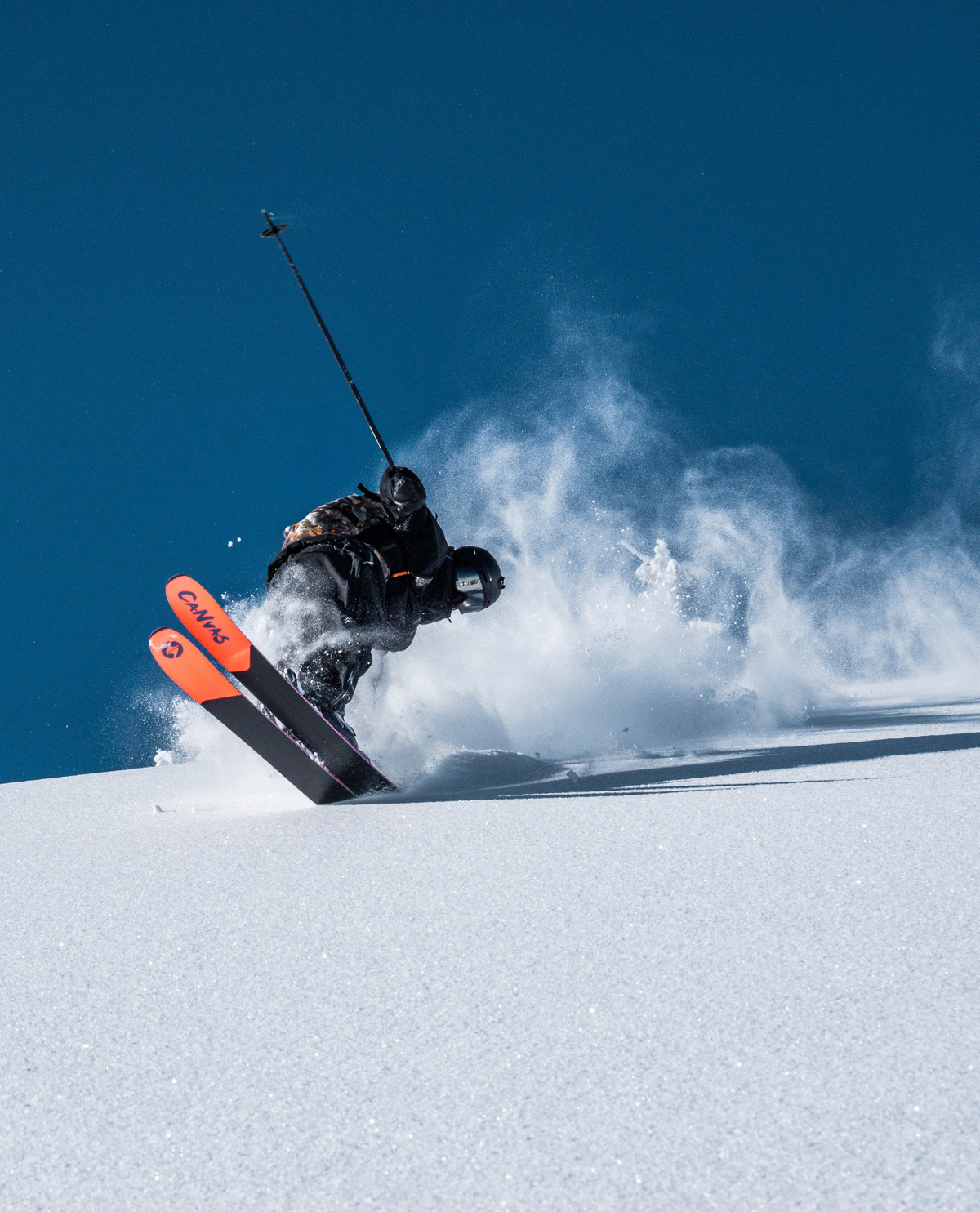Skidåkare som svänger i djupt puder med Blizzard Canvas 118 freerideskidor som har orangea tuppar.