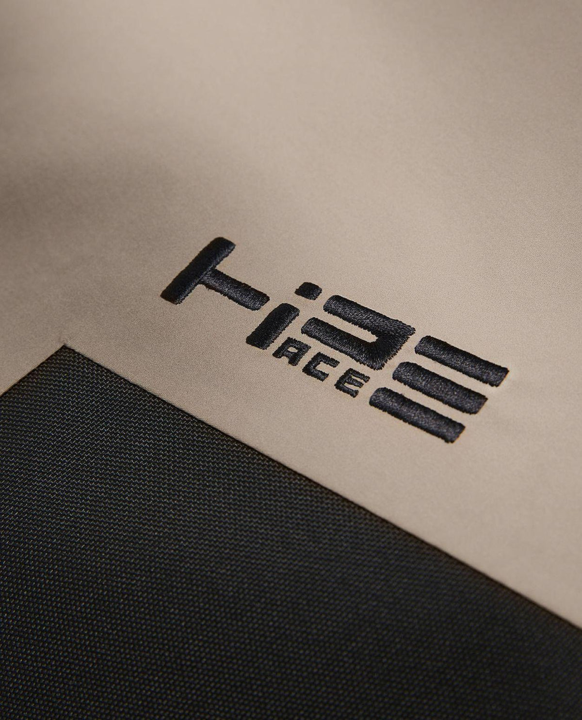 Närbild på broderad HiPE-logotyp på Peak Performance Edge 3L AOP Bib Pants dam i färgen Beam Fade.