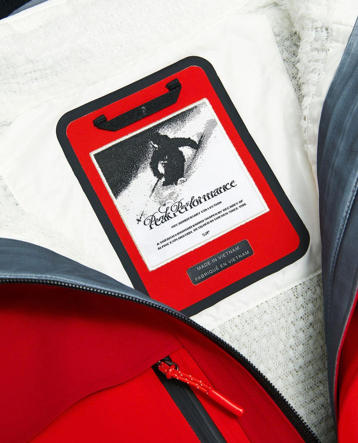Närbild på inneretikett och logotyp i Peak Performance 40Y R&D Long Gore-Tex Shell Jacket för dam.