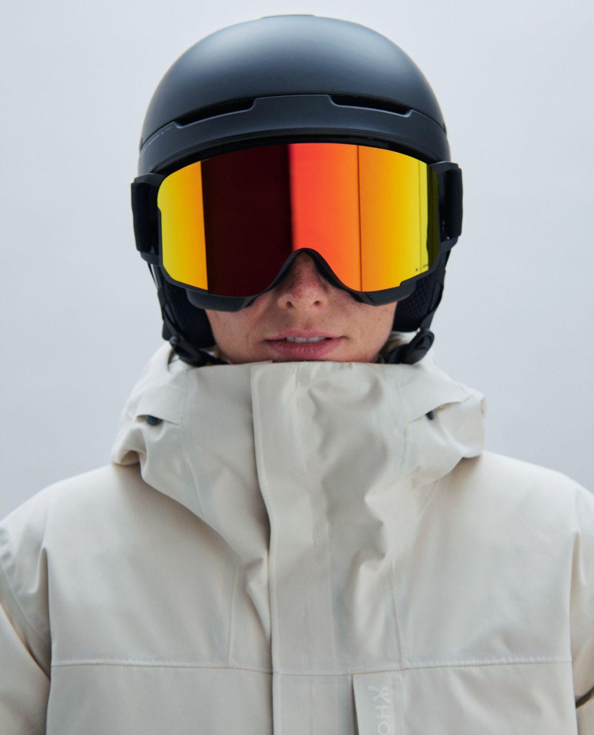 POC Nexal skidglasögon i Uranium Black med Partly Sunny Orange spegellins och matchande svart hjälm.