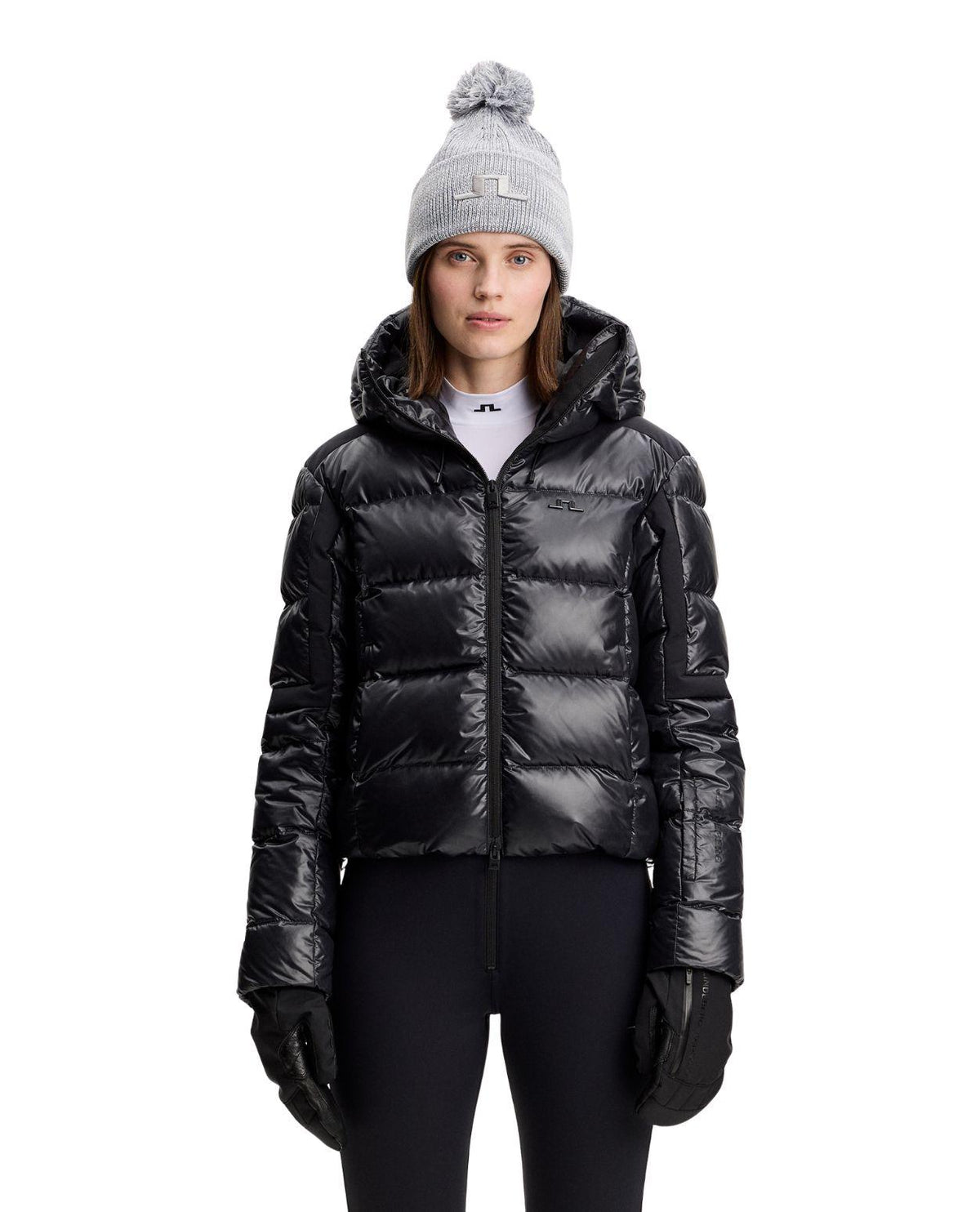 J.Lindeberg Nerina Down Jacket Women i svart, visad framifrån på modell med mössa och skidjacka.