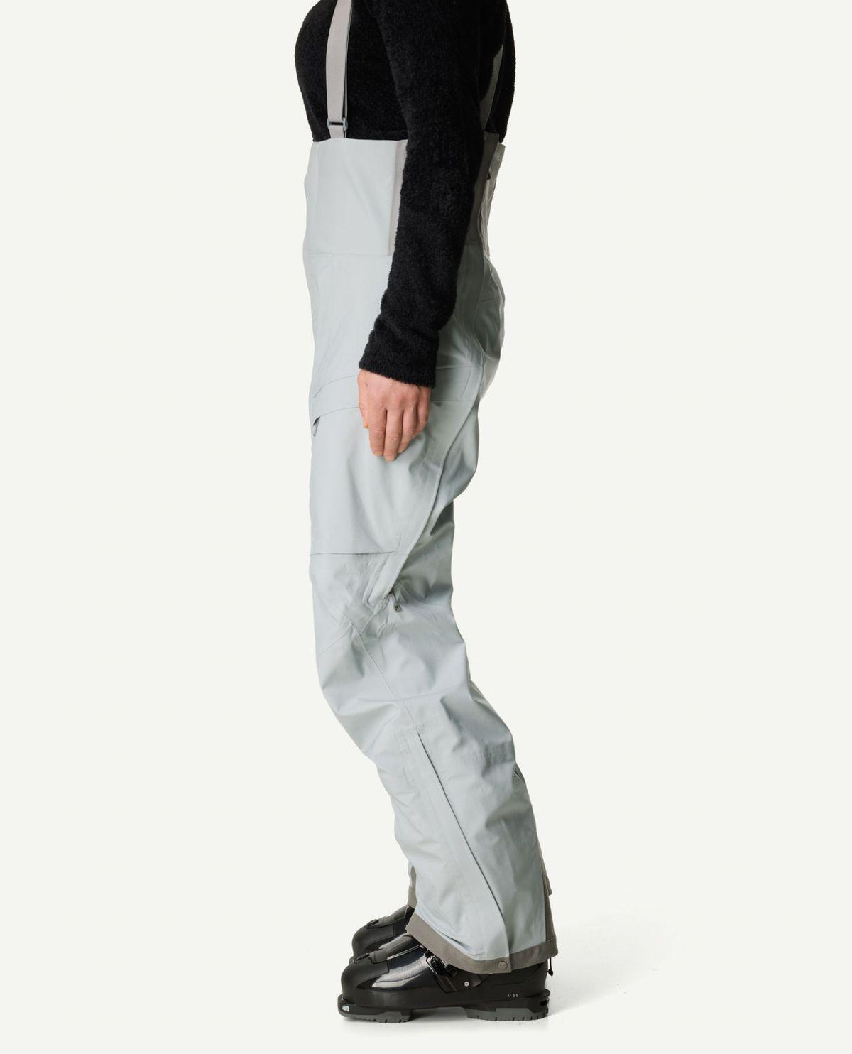 Houdini Rollercoaster Bib Pants dam i ljusgrått set från sidan med pjäxor.