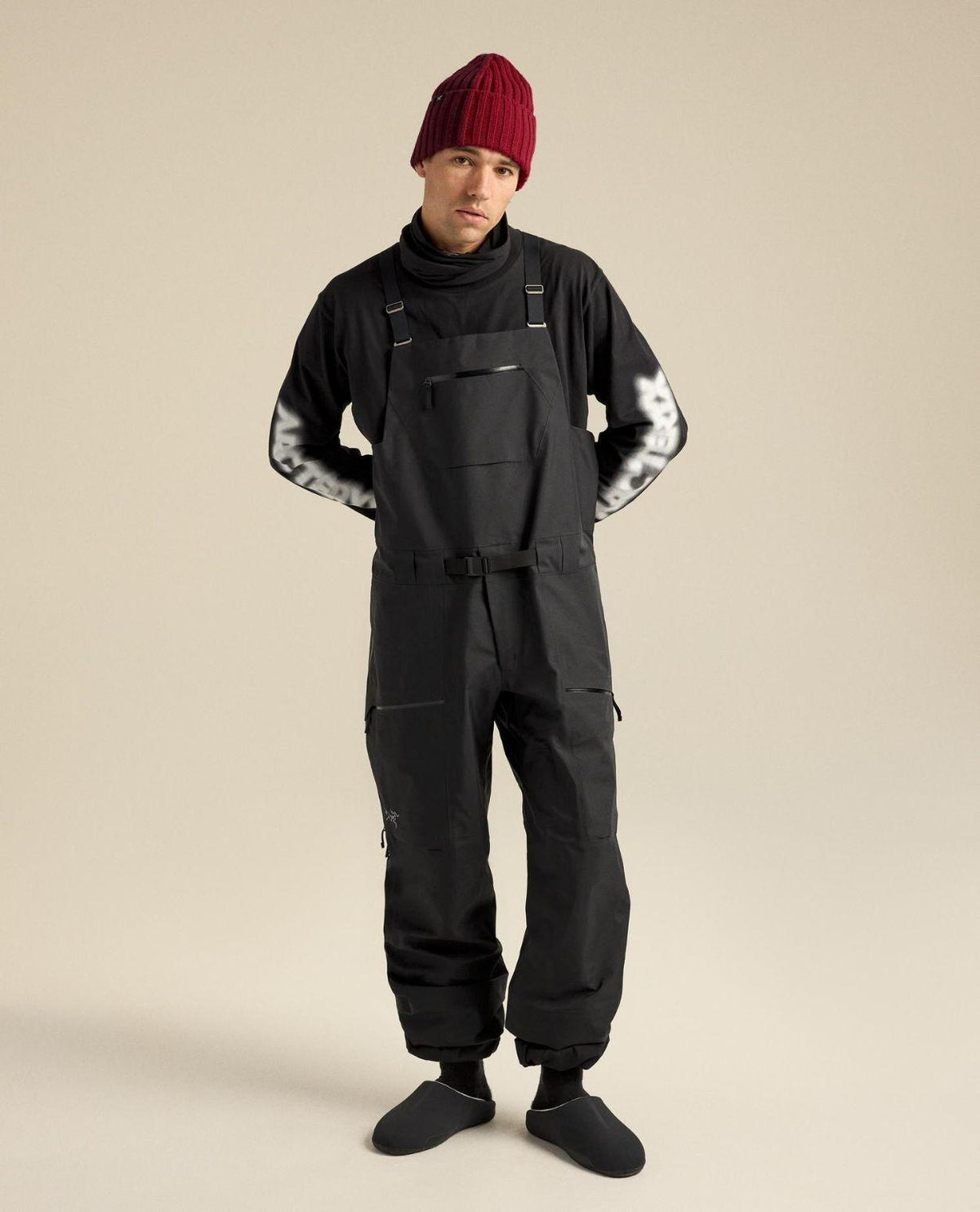 Arc'teryx Sabre Bib Men i svart färg för herrar, visad framifrån med röd mössa.