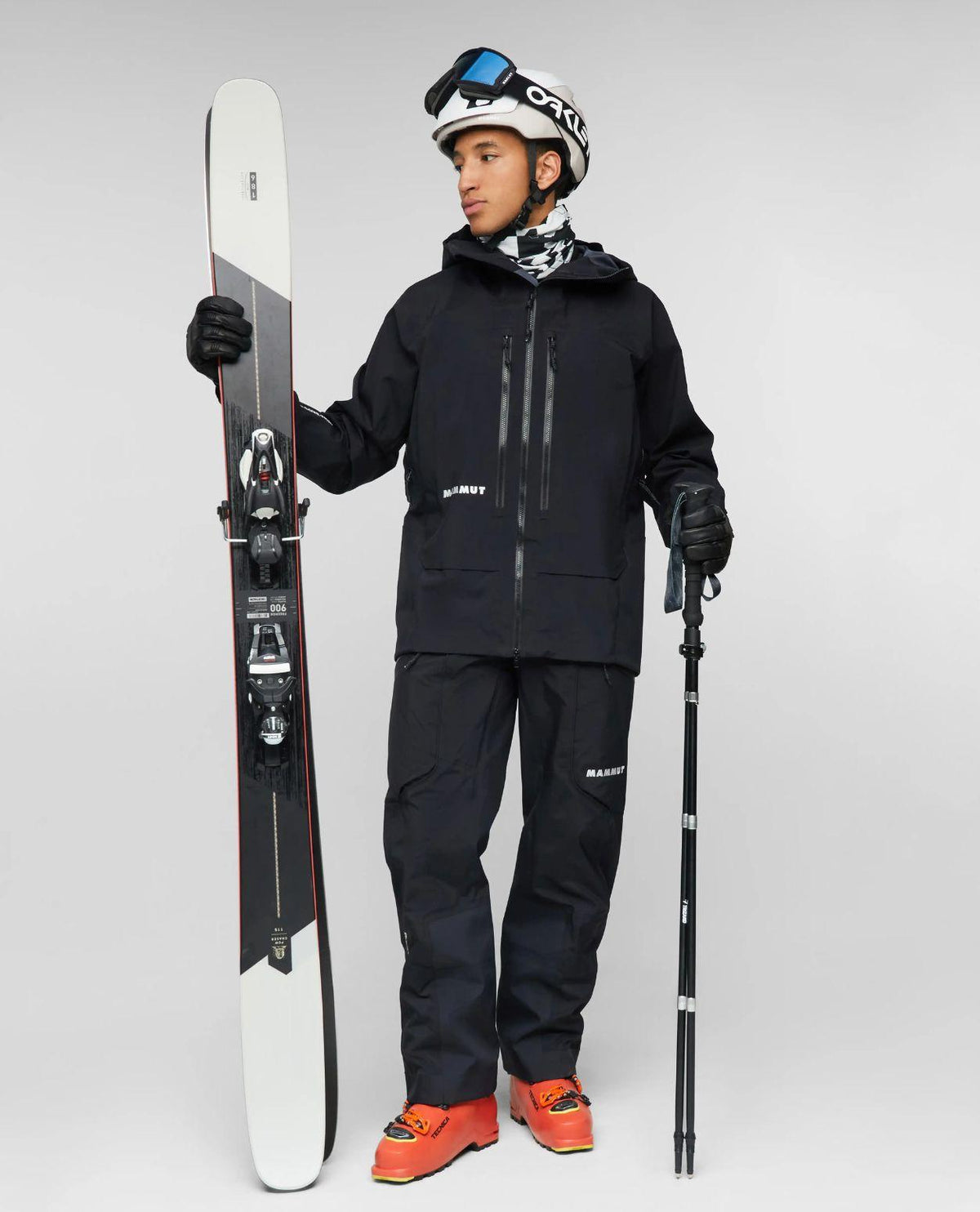 En skidåkare i svarta Mammut Eiger Free Pro HS Bib Pants håller i skidor.
