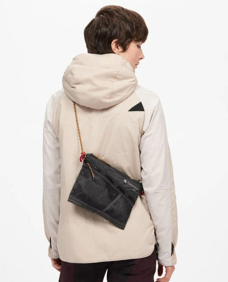 Klättermusen Algir Accessory Bag Medium i färgen raven buren över axeln av en skidåkare.