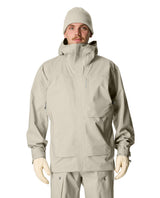 Manlig skidåkare iförd grön-grå Houdini Rollercoaster Jacket II och matchande mössa.