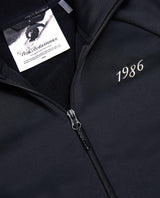Peak Performance 40Y Rider Zip Hood i svart med jubileumsetikett och tryckt årstal 1986.