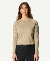 En kvinna iklädd Houdini Puremerino Crew underställströja i färgen powder green och svarta byxor.