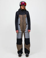 Skidåkare i dammodellens Peak Performance Vertical Gore-Tex Pro Bib Pants i färgen Terrain Tan och ljusgrå framifrån.
