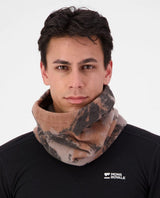Person bär Mons Royale Pileup Fleece Neck i mönstret mtn camo orange.