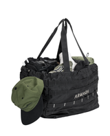 Armada AR Gear Haul 50L Tote fylld med skidutrustning och en grön keps hängande på kanten.