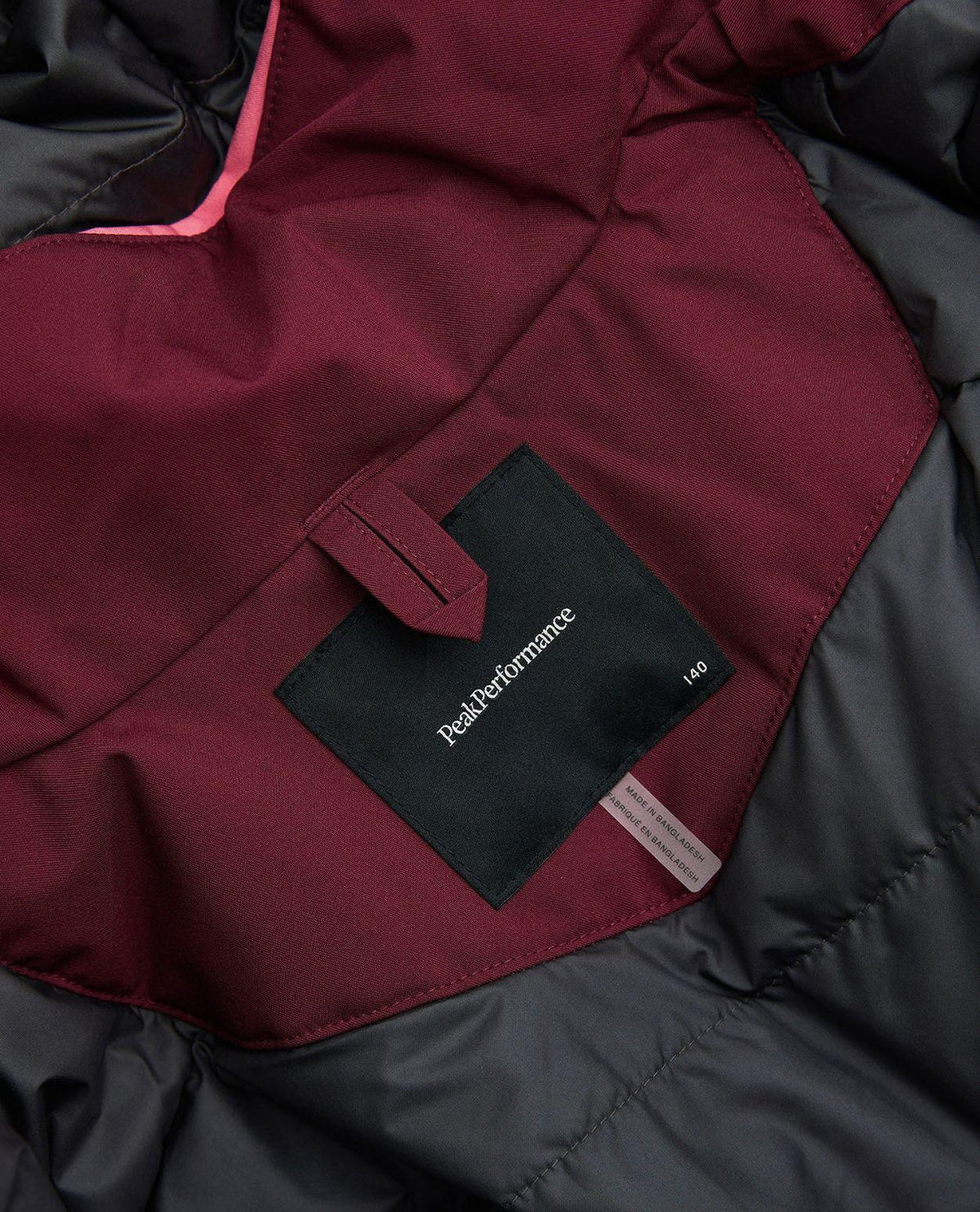 Närbild på inneretikett och logotyp i Peak Performance Gravity Insulated Jacket Junior.