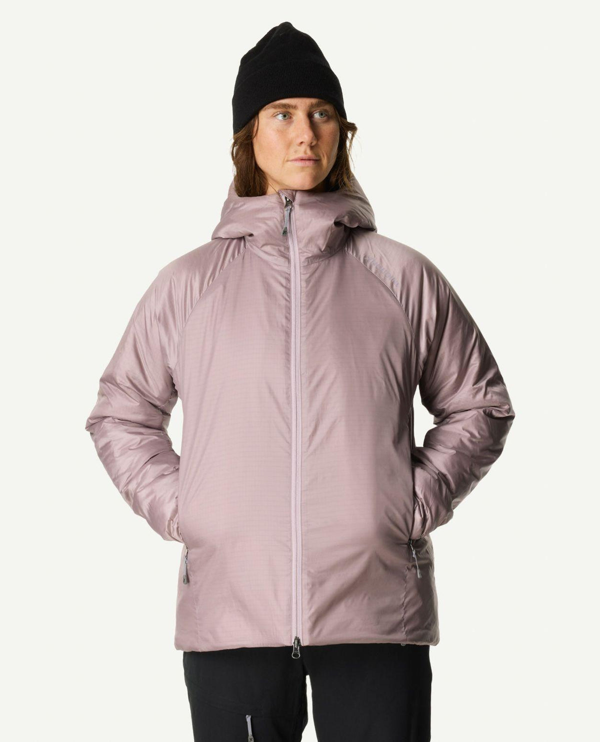 Kvinna iklädd Houdini Dunfri damjacka i lila färgen Sky Purple och svart mössa.