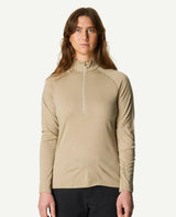 Kvinna iklädd Houdini Puremerino Halfzip i färgen powder green mot ljus bakgrund.