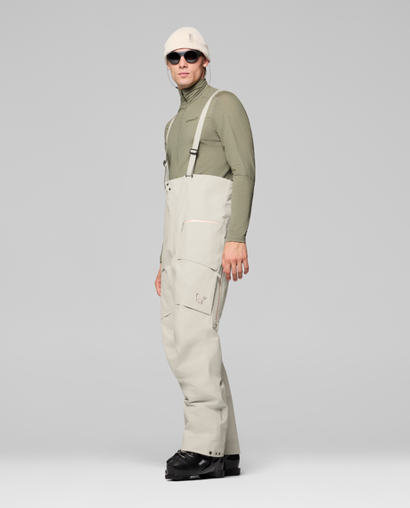 Norrøna Møre Gore-Tex Salopette Men i färg oatmeal för herrar på modell sedd från sidan. Alpingaraget