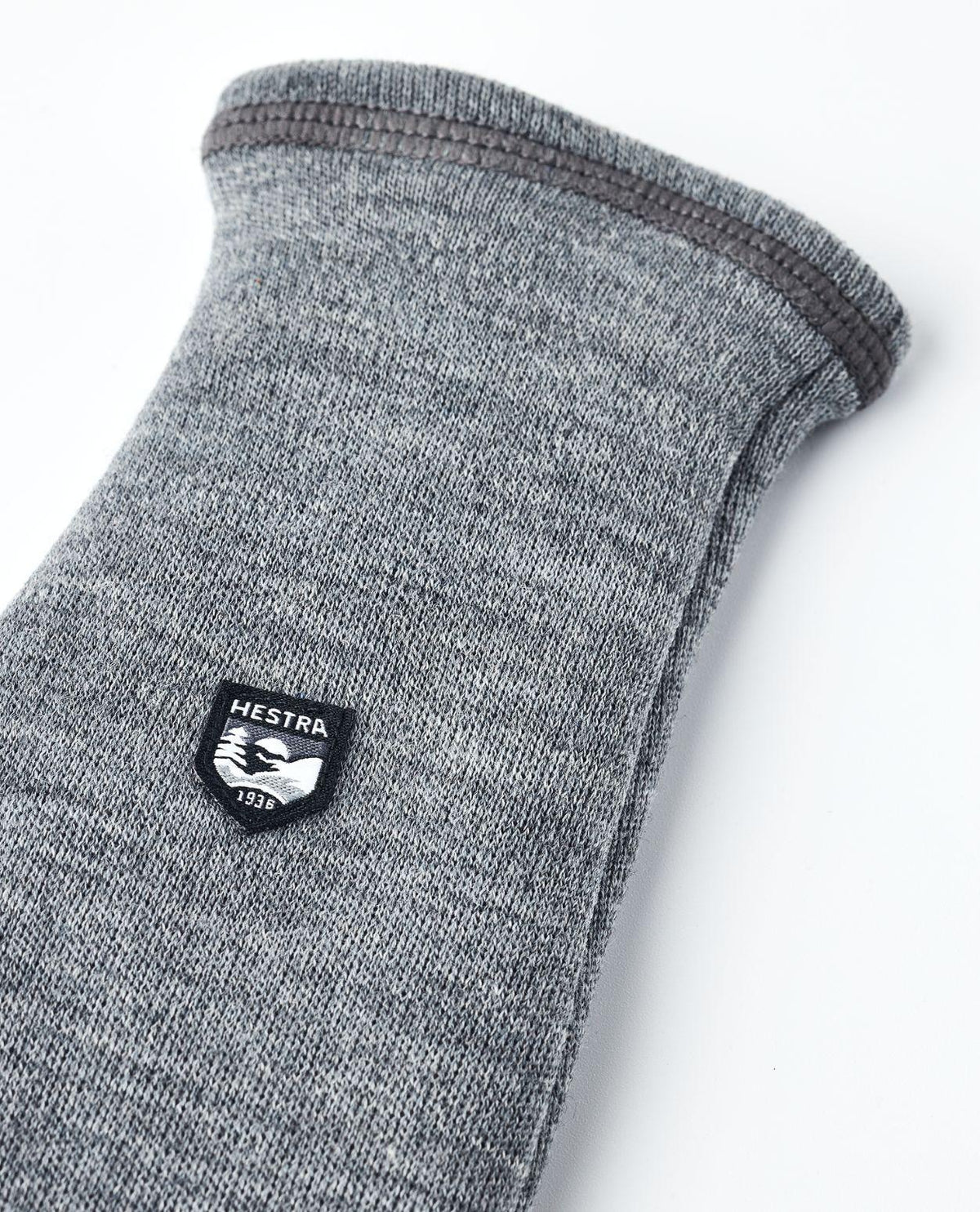 Hestra Gravita Merino Liner Mitt i grå merinoull med tydlig logotypdetalj.