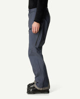 Sida av Houdini Ride Pants II skidbyxor i färgen Hombre Blue på en man som har pjäxor på sig.