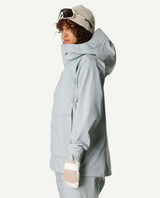 Houdini Rollercoaster Jacket II Women i färgen Breaker Gray på modell sedd från sidan med huva, mössa och skidglasögon.