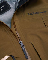 Närbild på broderad logotyp och dragkedja på Peak Performance Alpine Gore-Tex 3L Jacket i färgen Meadow Moss.