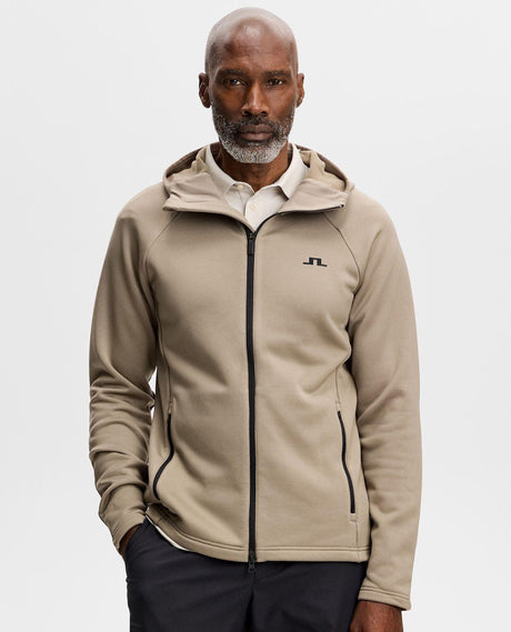 Manlig modell bärande J.Lindeberg Pollock Polartec Hood i brunsåst färgsättning.