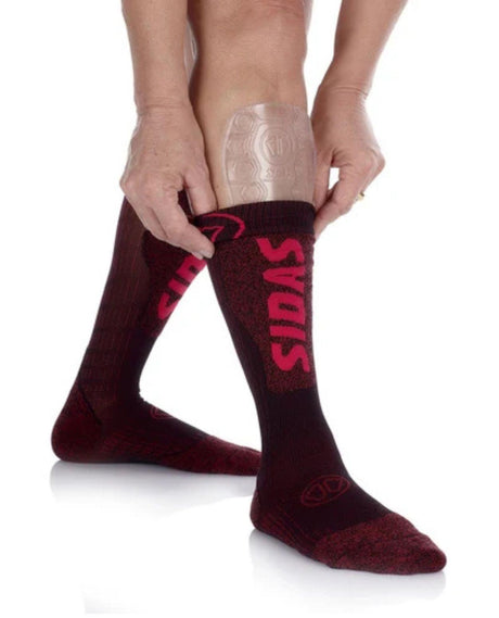 Person som sätter på sig Sidas Shin Protector EVO och drar en mörk strumpa över benskyddet på smalbenet.