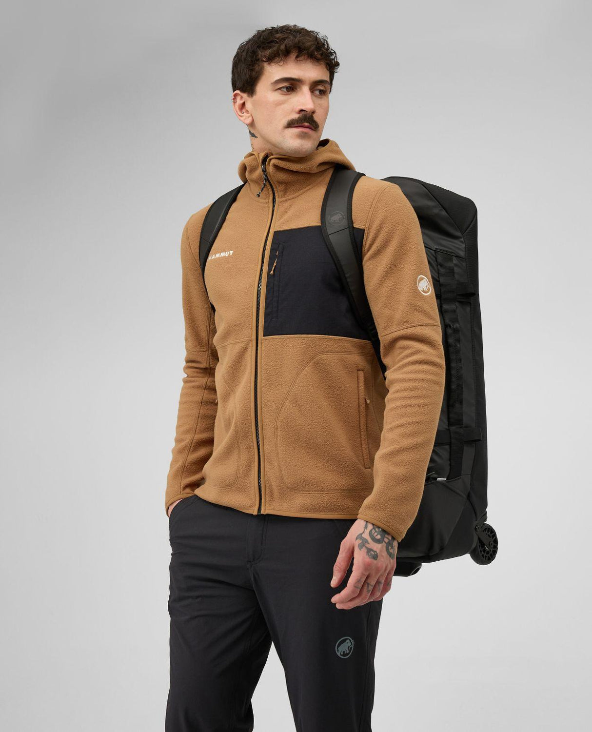 Man som bär den svarta resväskan Mammut Wheeled Cargo 90 som ryggsäck.