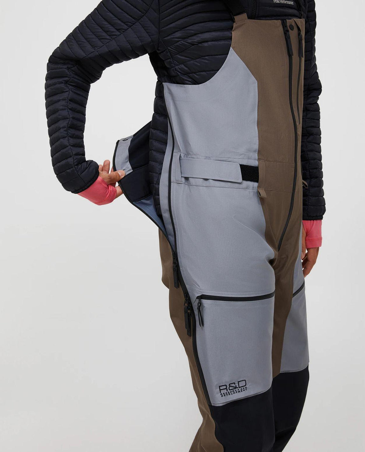 Peak Performance Vertical Gore-Tex Pro Bib Pants för damer i färgerna terrain tan och ljusgrå, där sidan av byxan visas med dragkedja.
