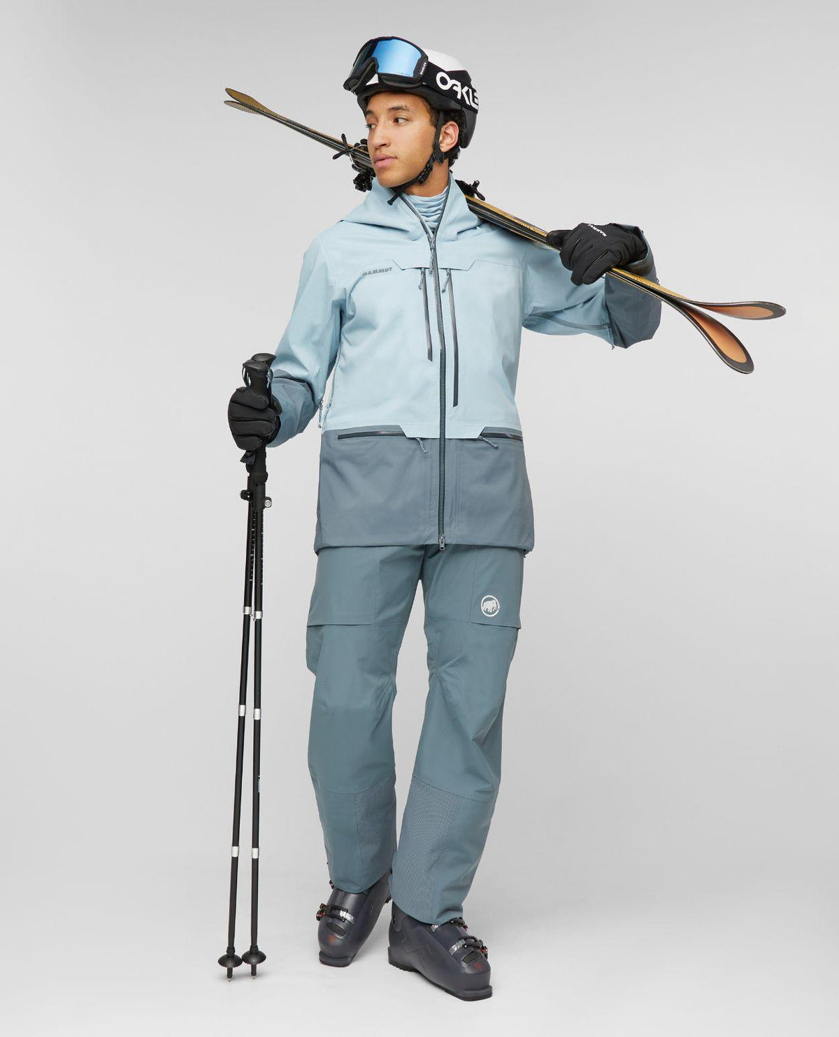 Skidåkare i Mammut Haldigrat HS Hooded Jacket i färgen Nebla-Strata med skidor på axeln i studion.