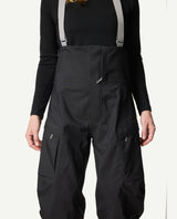 Närbild på Houdini Rollercoaster Bib Pants II skidbyxor för dam i svart med grå hängslen och benfickor.