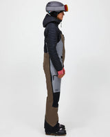 Skidåkare i profil som bär Peak Performance Vertical Gore-Tex Pro Bib Pants för damer i färgerna brun och ljusgrå.