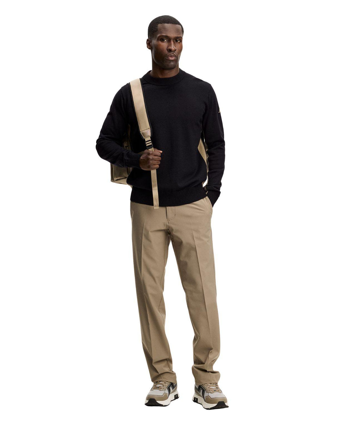 J.Lindeberg Chester Side Stripe Knit Crew i svart på modell med beige byxor och väska.