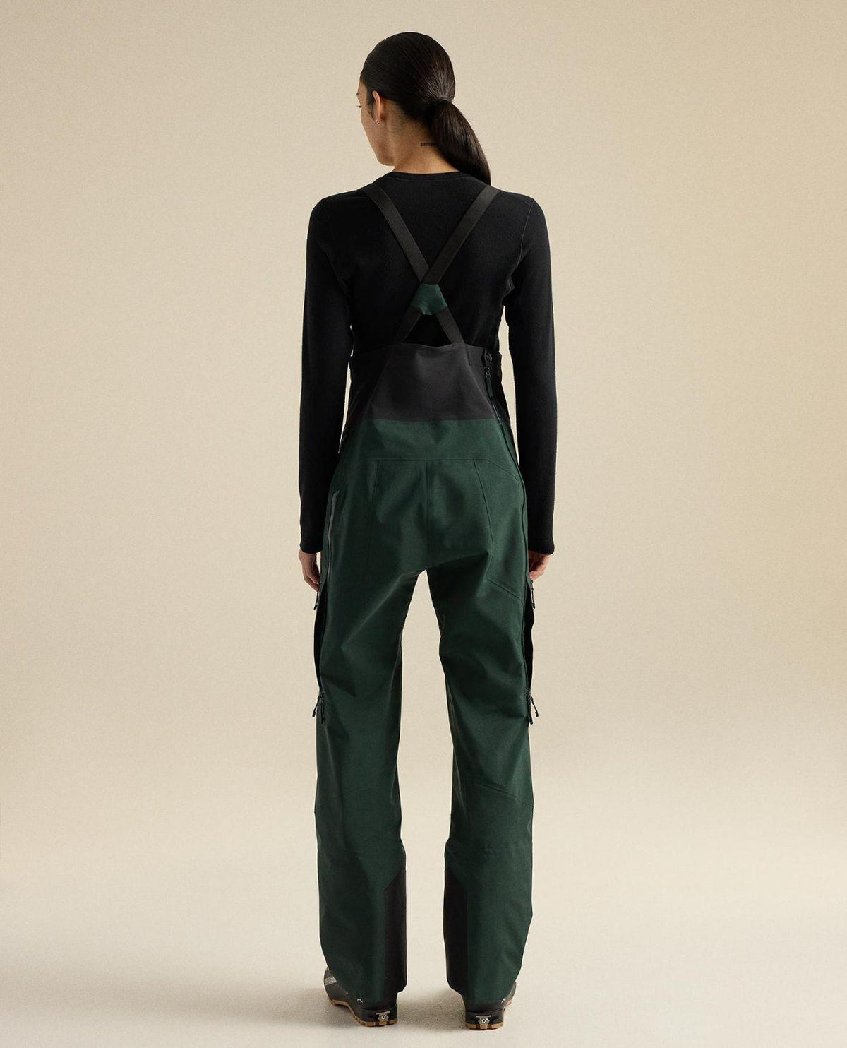 Arc'teryx Rush Bib Pant Women i färgen dark jade ses bakifrån, visande hängslen och hållbart GORE-TEX-material.