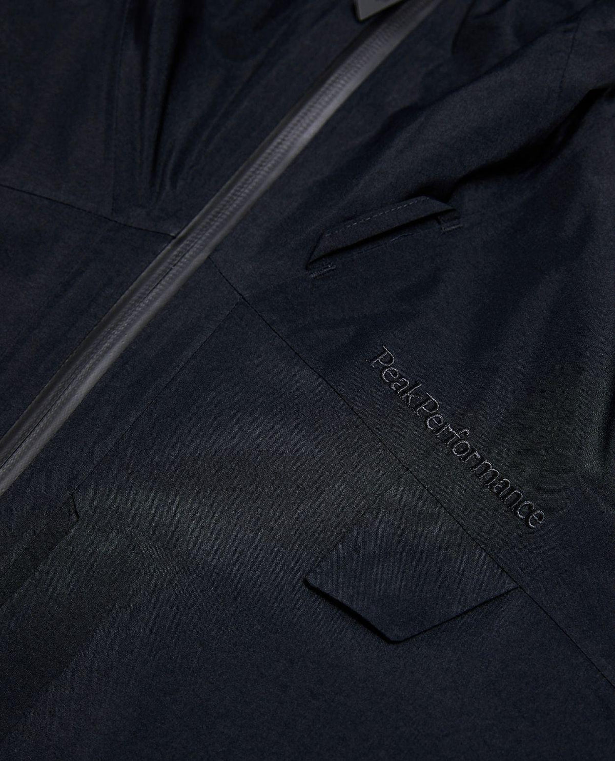 Närbild på den svarta skidjackan Alpine Gore-Tex Insulated Jacket från Peak Performance med broderad logotyp.