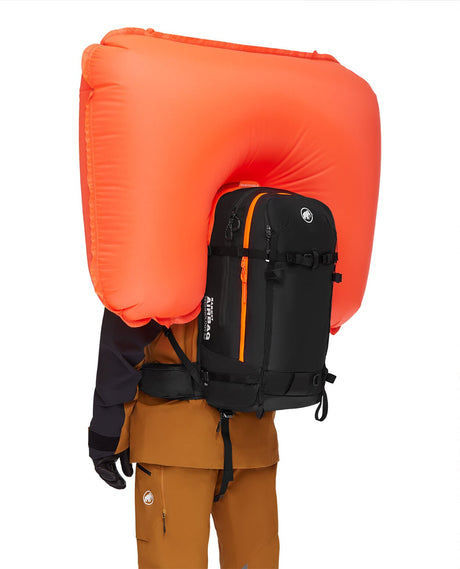 En person som bär en svart Mammut Pro 35 Removable Airbag 3.0 lavinryggsäck med den orangea krockkudden uppblåst, sedd bakifrån.